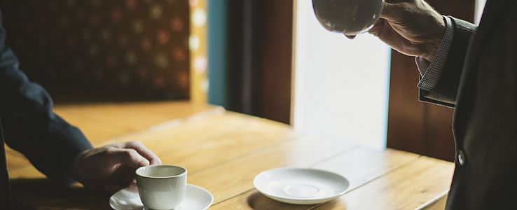 Male hands in business suits holding coffee cups