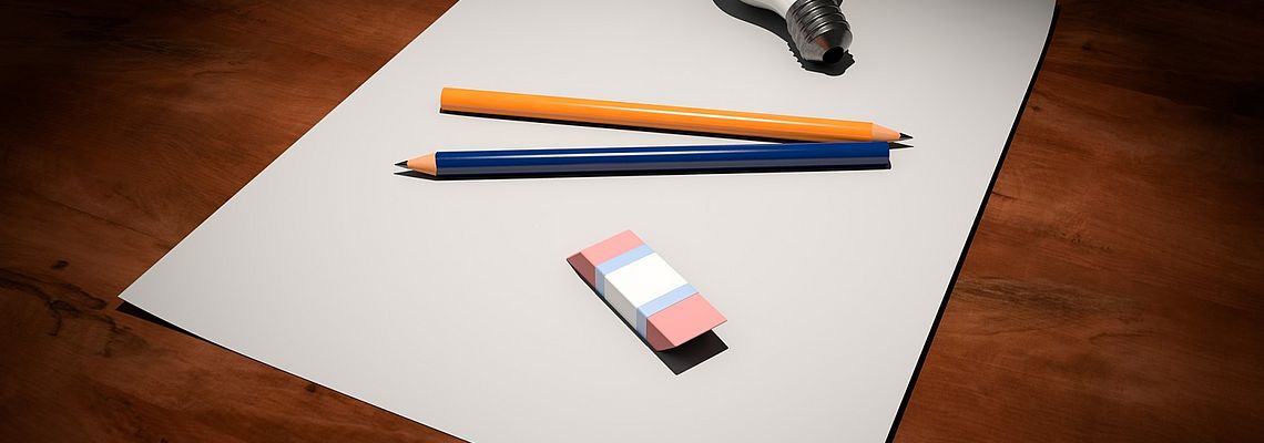Pencils, rubber and a lightbulb on white paper sheets