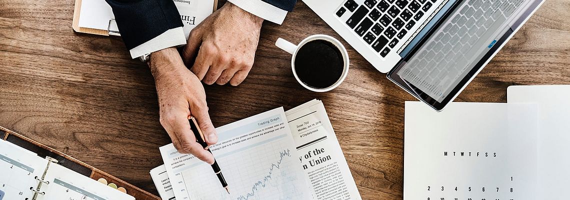 Business hands pointing to a graphic next to coffee mug and laptop