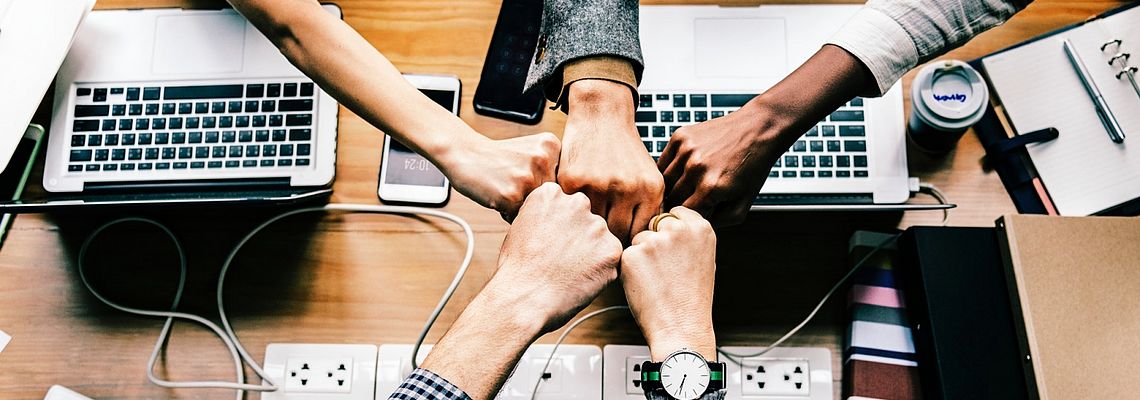 Collective fistbump over desk with laptops