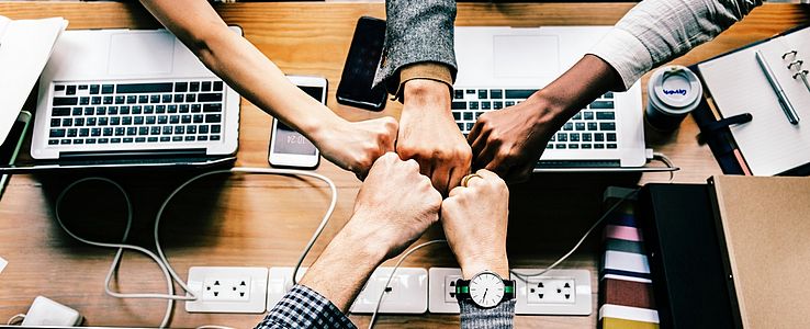 Collective fistbump over desk with laptops