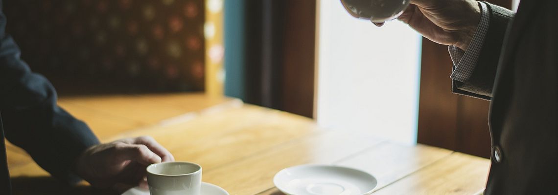 Male hands in business suits holding coffee cups
